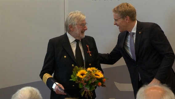 Ministerpräsident Daniel Günther überreicht einem Mann einen Blumenstrauß. Ministerpräsident Daniel Günther überreicht einem Mann einen Blumenstrauß. © Archiv Foto: Archiv