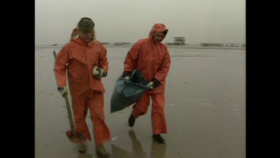 Zwei Männer in Orangen Anzügen gehen über das Watt © NDR 