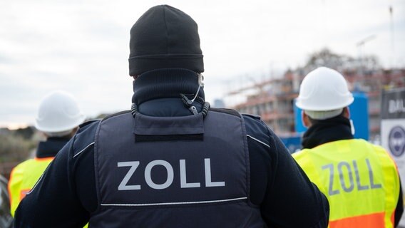 Drei Zoll-Beamte stehen mit dem Rücken zur Kamera. © dpa-Bildfunk Foto: Sebastian Gollnow