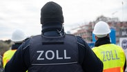 Drei Zoll-Beamte stehen mit dem Rücken zur Kamera. © dpa-Bildfunk Foto: Sebastian Gollnow