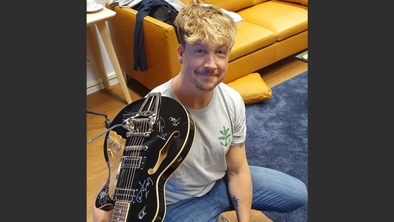 Sänger Samu Haber unterschreibt eine Duesenberg Gitarre. © NDR 