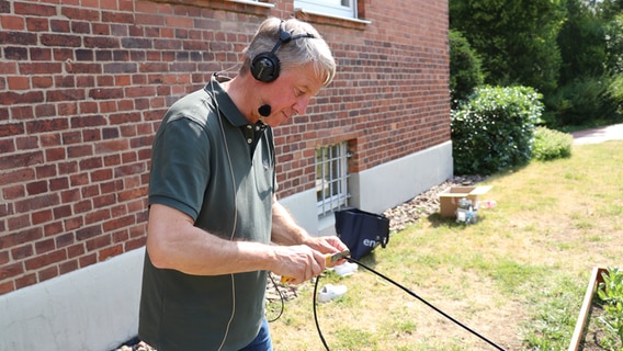 Ralf schneidet Schläuche für das Beet © NDR Foto: Jasmin Janosch