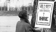 Eine Frau steht vor einem Protestplakat gegen den Bau der Atommülldeponie Gorleben im Kreis Lüchow-Dannenberg. © dpa 