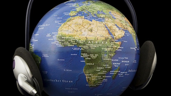Kopfhörer vor dunklem Hintergrund auf einen Globus gesetzt. © panthermedia Foto: GünterSlabihoud