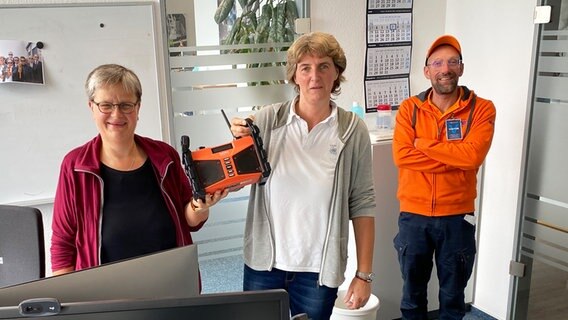 Schorse übergibt ein Dabbi DAB+ Baustellenradio an Helga Schöning und ihre Frau Bärbel Vollhardt (v.l.). © NDR Foto: Bernd Drechsler
