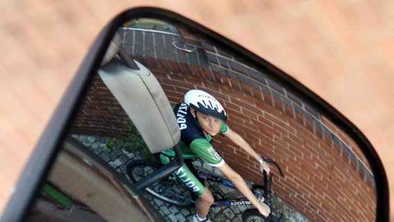 Auf einem Fahrrad sitzende Polizisten in einem Außenrückspiegel eines Autos © picture-alliance/dpa Foto: Guido Bergmann