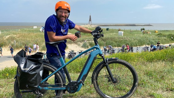 Schorse mit seinem E-Bike vor der Kugelbake in Cuxhaven © NDR Foto: Bernd Drechsler