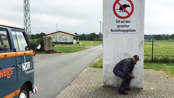 Schüssel-Schorse hockt sich vor ein Hinweisschild © NDR Foto: Andi Gervelmeyer