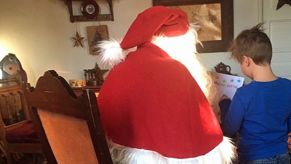 Ein kleiner Junge sitzt bei dem Weihnachtsmann auf dem Schoß. © NDR Foto: Hendrik Millauer