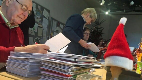 Die "Weihnachtsengel" sitzen am Tisch und schauen die Wunschzettel durch © NDR Foto: Hendrik Millauer