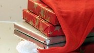 in Weihnachtspapier eingepackte Bücher unter einer Weihnachtsmütze © picture-alliance / Lehtikuva / Hehkuva Foto: Ismo Pekkarinen