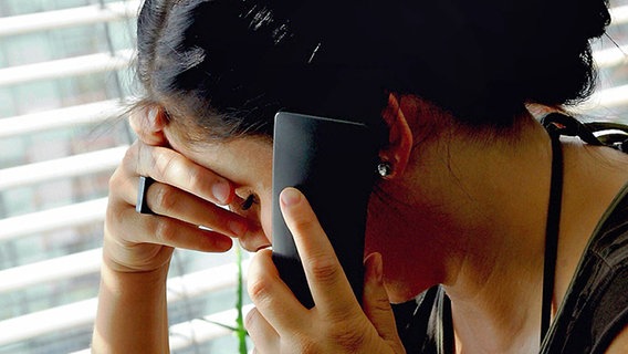 A depressed woman is on the phone.  © picture-alliance / ZB Photo: Marion Gröning