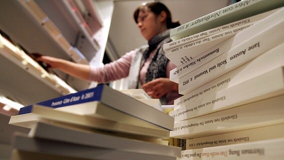 Eine Verlagsmitarbeiterin sortiert Bücher in Regale ein. © picture-alliance/dpa Foto: Frank May