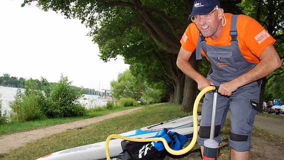 Schüssel-Schorse pumpt ein Surfbrett auf. © NDR Foto: Jessi Schantin