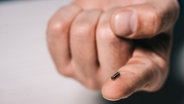 Ein Mann hat auf einem Zeigefinger einen Mikrochip liegen. © Colourbox Foto: -
