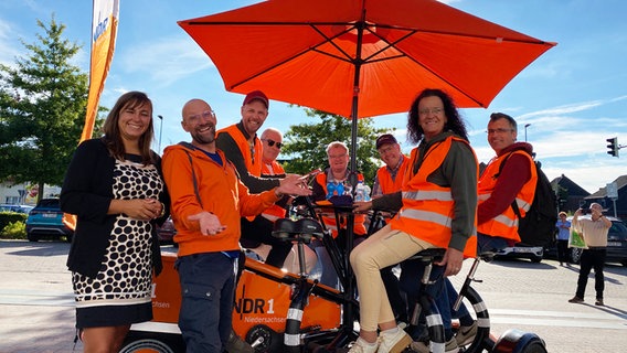 Kristin König, Schorse, Andi Gervelmeyer, Hans-Werner Aschoff, Claudia Pförtner, Gernot Pförtner, Thomas Aldag und Michaela Schal (v.l.) auf dem Team-Rad in Bookholzberg. © NDR Foto: Bernd Drechsler