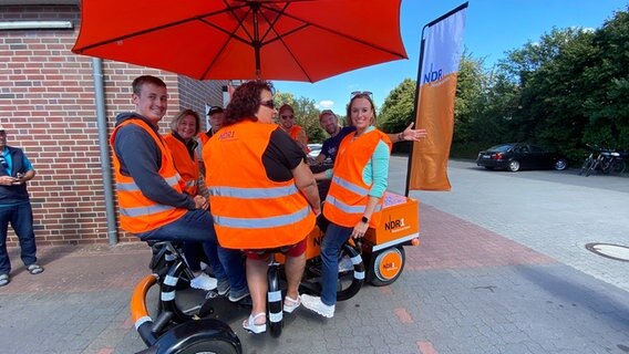 Stefan Gerter, Birgit Reuter, Werner Meyer, Andi Gervelmeyer, Schorse, Kira Reuter und Rosemarie Martens (v.l.) auf dem Team-Rad in Wüsting. © NDR Foto: Bernd Drechsler