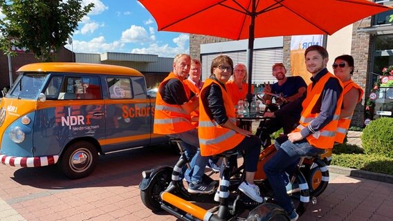 Kerstin Borm, Olaf Kretschmer, Petra Knetemann, Silvia Kruse, Schorse, Dörthe Wordtmann und Sebastian Ross (v.l.) auf dem Team-Rad in Edewecht. © NDR Foto: Bernd Drechsler