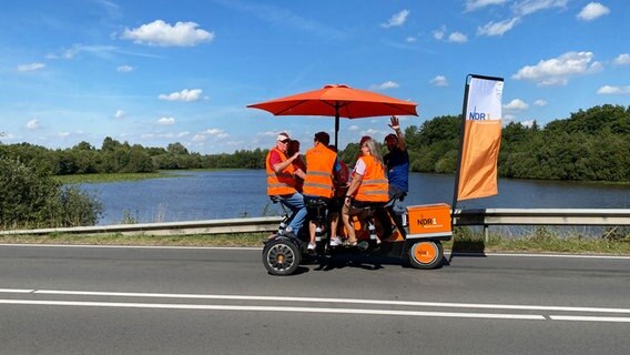 Zwischen Ostrhauderfehn und Rhauderfehn fahren Lothar Fahl, Manfred Ammermann, Nicole Beck, Andreas Meiners, Horst Tinnemeyer, Schorse und Evelyn Misehke auf dem Team-Rad. © NDR Foto: Bernd Drechsler