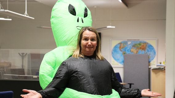 Susanne Neuß überrascht die anderen Moderator*innen im Alien-Kostüm. © NDR Foto: Luisa Müller