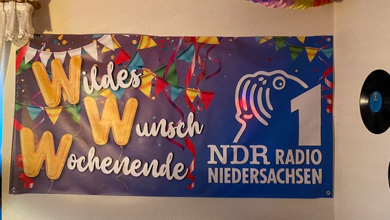 Schorse übergibt ein Dabbi DAB+ Radio beim WWW an Dennis Meister. Bei der Party hängt ein WWW-Banner. © NDR Foto: Bernd Drechsler