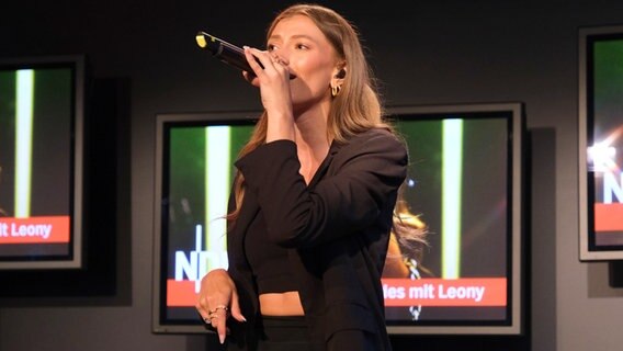 Leony bei NDR 2 am 5. Juli 2023: sie singt mit einem Mikrofon in der Hand, im Hintergrund Bildschirme mit ihrem Bildnis © NDR 2 Foto: Viktoria Wanka