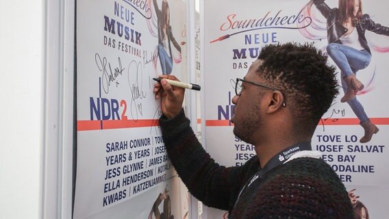 Kelvin Jones unterschreibt auf einem Plakat beim Soundcheck Neue Musik festival in Göttingen. © NDR Foto: Axel Herzig