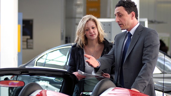 Eine junge Frau lässt sich von einem Autohändler beraten © dpa 