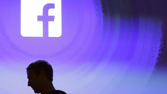 Silhouette von Mark Zuckerberg vor Facebook-Logo in der Zentrale in Menlo Park © dpa Foto: Marcio Jose Sanchez/AP