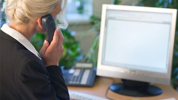 Eine Frau telefoniert, während sie am Computer sitzt.  Foto: Patrick Pleul
