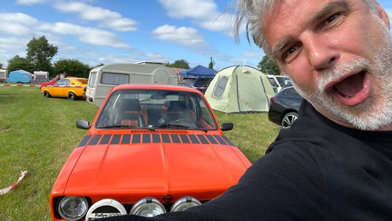 Der NDR 2 Moderator Jens Hardeland steht vor einem alten Opel im Rahmen von Wünsch dir deinen NDR © NDR Foto: NDR