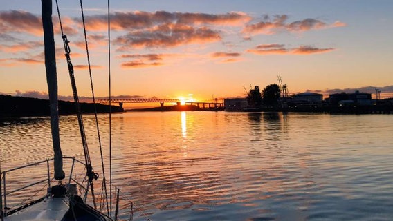 Die Sonne geht über dem Nord-Ostsee-Kanal auf. Auf dem Foto zu sehen sind ein Schiff, eine ruhige See und Kräne. © NDR 2 Foto: NDR 2 Hörer Phili