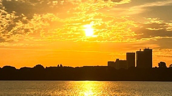 Die Sonne geht über der Alster in Hamburg auf. Sie hüllt die Skyline in ein orange-gelbes Licht. Schäfchenwolken schmücken den Himmel. © NDR 2 Foto: NDR 2 Hörerin Katy