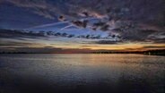 Die Sonne geht über der Ostsee in Heiligenhafen auf. Der Horizont ist orangefarben erleuchtet, Schäfchenwolken ziehen über den Himmel. © Privat Foto: NDR 2 Hörer Michi