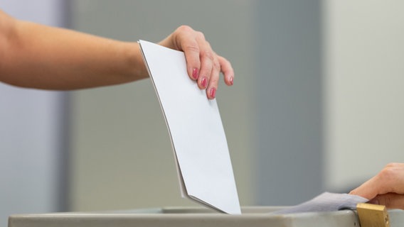 Eine Wählerin wirft bei der Stimmabgabe den Wahlzettel in eine Wahlurne.  Foto: Robert Michael