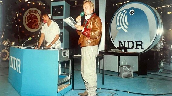 Uwe Bahn hinter einem Mischpult und Hape Kerkeling mit Mikrofon auf der Bühne bei "Du und deine Welt" Ende der Achtziger. © NDR 2 