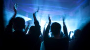 Menschen tanzen in einem Club. © IMAGO / Westend61 
