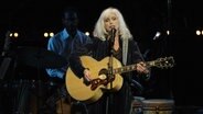 Die Musikerin Emmylou Harris singt 2018 bei einem Konzert in Los Angeles und spielt Gitarre. © IMAGO / MediaPunch 