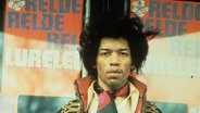 Der Gitarrist Jimi Hendrix steht vor Plakaten © picture alliance / Photoshot 