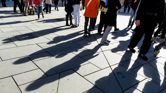 Menschen gehen über eine Straße und werfen Schatten. © Colourbox Foto: Erwin Wodicka