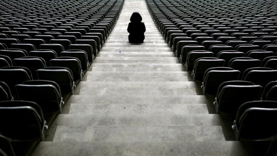 Eine junge Frau sitzt auf den Treppen eines Stadions zwischen den Sitzreihen © LauCam / photocase.de Foto: LauCam