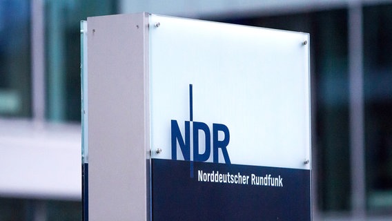 Ein Lichtkasten mit dem Logo des NDR vor einer gläsernen Häuserfront. © NDR Foto: Gitte Alpen