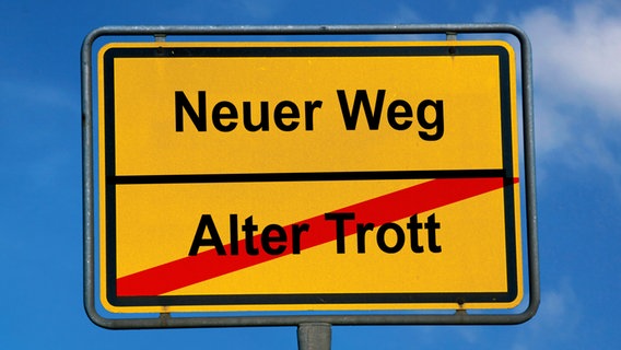 Ein Ortschild mit den Aufschriften "Alter Trott" (durchgestrichen) und "Neuer Weg" mit Pfeil © picture-alliance Foto: Helga Lade