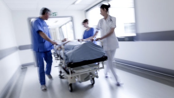 Arztteam rollt Patient auf Klinikbett durch einen Krankenhausflur. © panthermedia Foto: spotmatikphoto