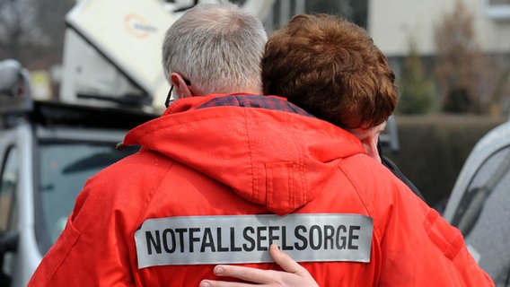 Ein Notfallseelsorger umarmt eine Frau. © dpa Foto: Norbert Försterling