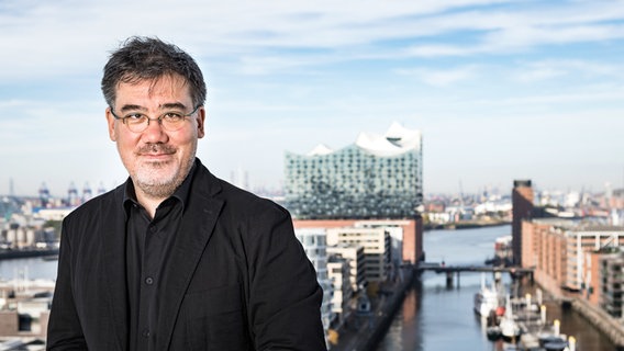 Alan Gilbert im Porträt vor der Skyline der Elbphilharmonie Hamburg © NDR Foto: Peter Hundert