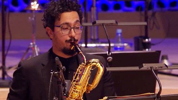 Screenshot aus dem Konzertmitschnitt aus der Elbphilharmonie Hamburg: Luigi Grasso von der NDR Bigband spielt Baritonsaxofon. © NDR Bigband Foto: Screenshot