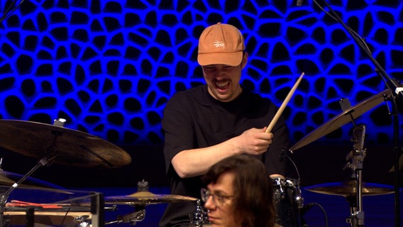 Screenshot: Schlagzeuger Silvan Strauss von der Gruppe TOYTOY spielt mit der NDR Bigband das Programm "Big Baroque" in der Elbphilharmonie Hamburg. © NDR Bigband Foto: Screnshot