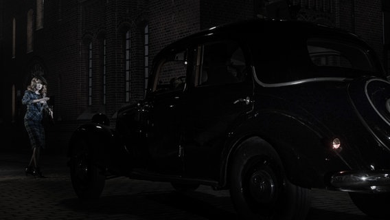 Screenshot: Eine Schauspielerin steht im Scheinwerferlicht eines Autos. © NDR Bigband Foto: Screenshot