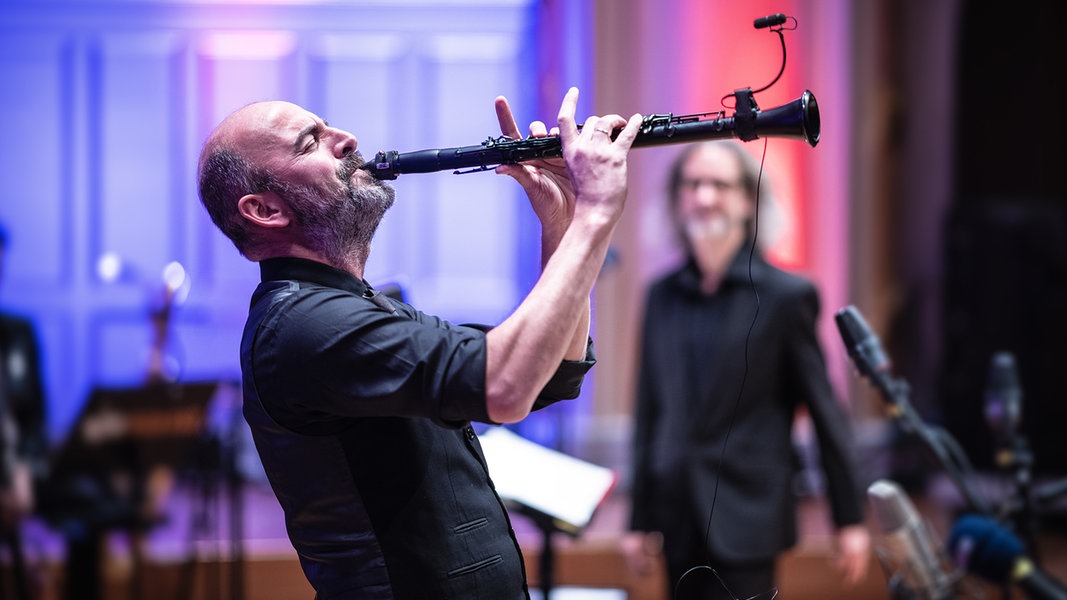 Kinan Azmeh plays clarinet. Conductor Wolf Kerschek out of focus in the background. 